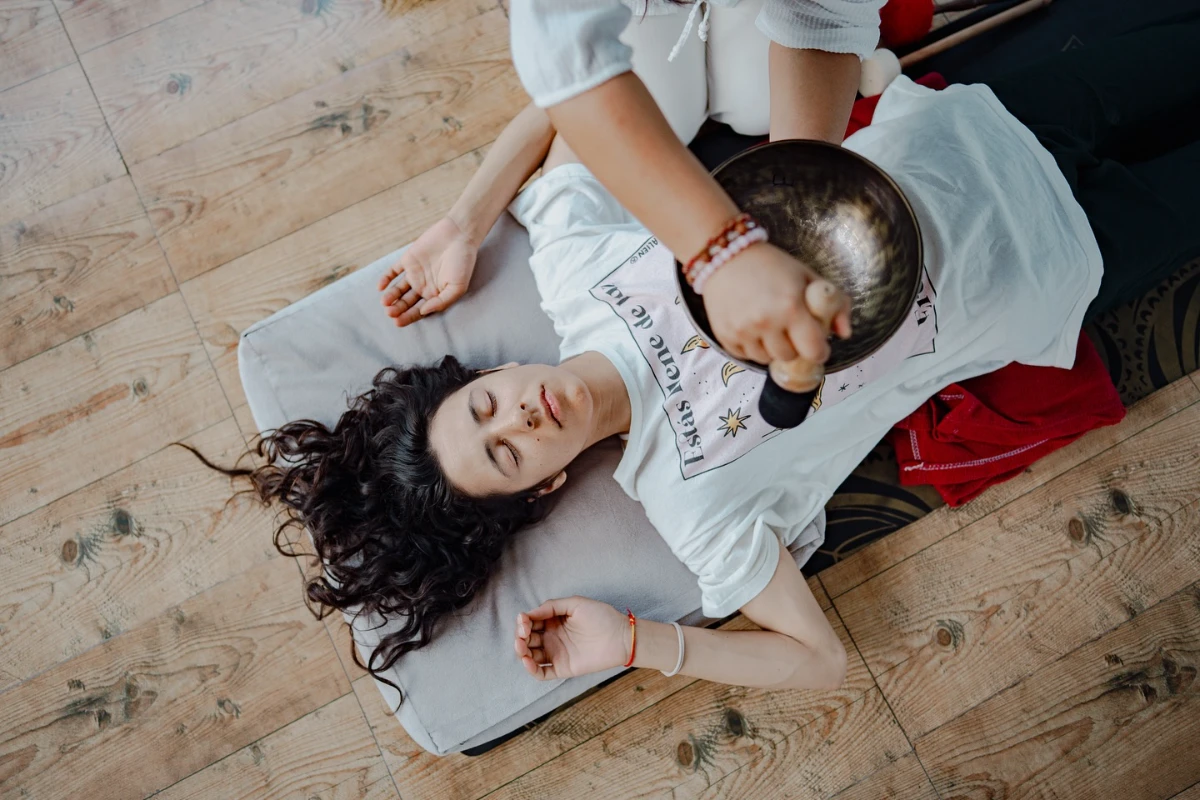 Eine große tibetische Schale wird während einer therapeutischen Sitzung über dem Körper gespielt