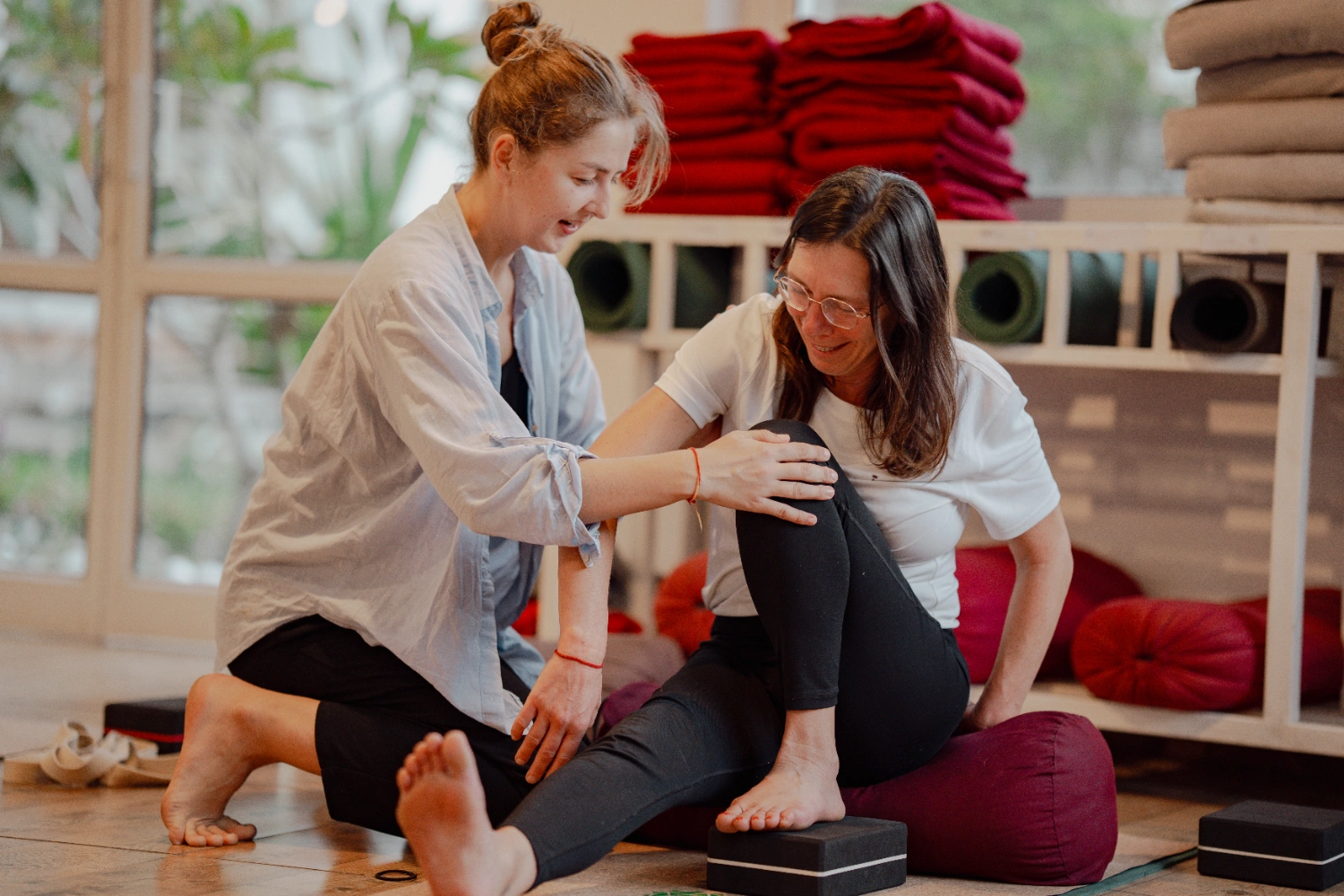 A teacher guiding a slow, supported restorative posture with props