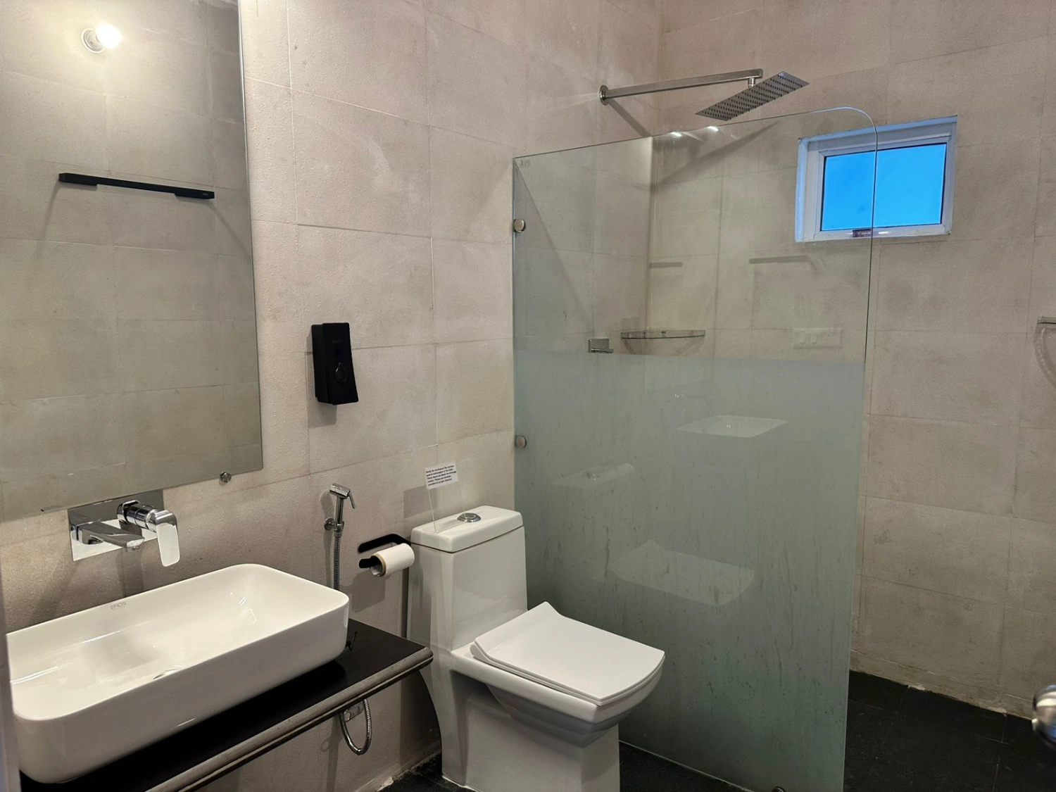 A clean, modern attached bathroom with a rain shower