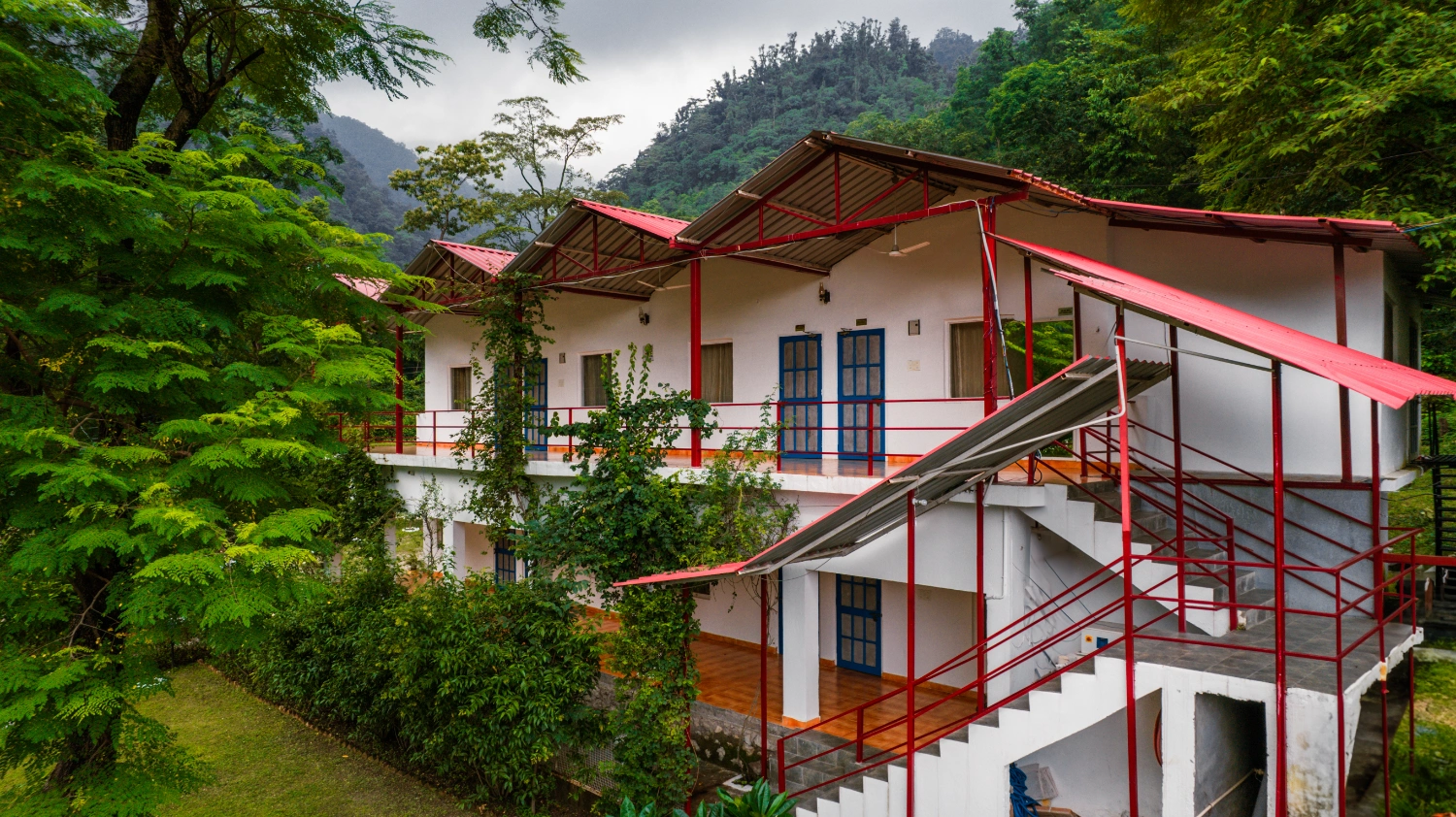 The green buildings of the Adhiroha ashram among the trees