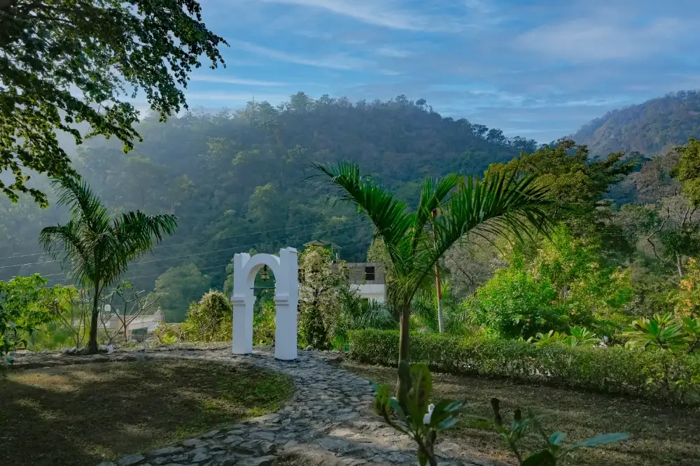 The white bell arch standing in the ashram gardens against the hills