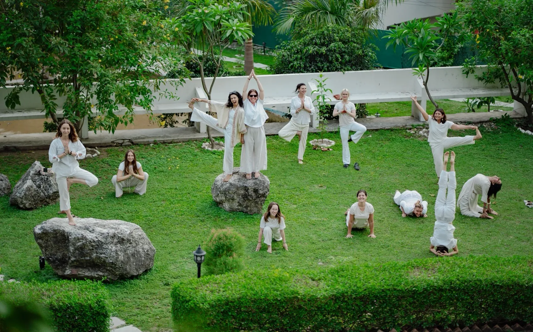 Students practising yoga safely in the green walled gardens of the Adhiroha ashram, Rishikesh